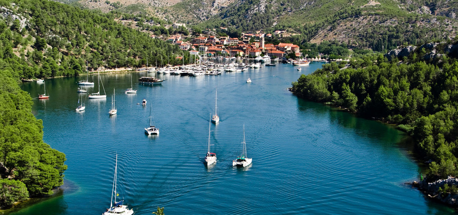 A Croatia yacht charter sails along blue waters by a harbour town